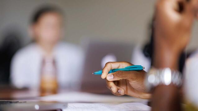 a women writing with the pen in focus
