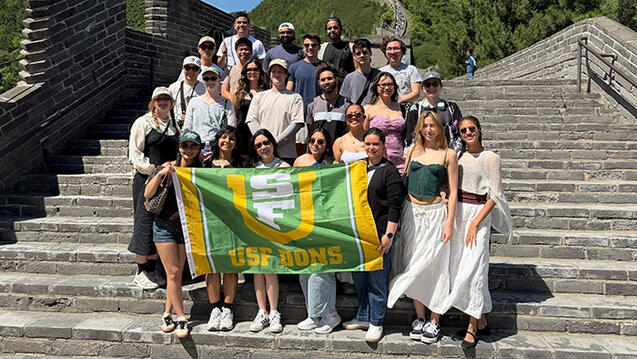 group of biotech students hold up a usf flag during a trip abroad