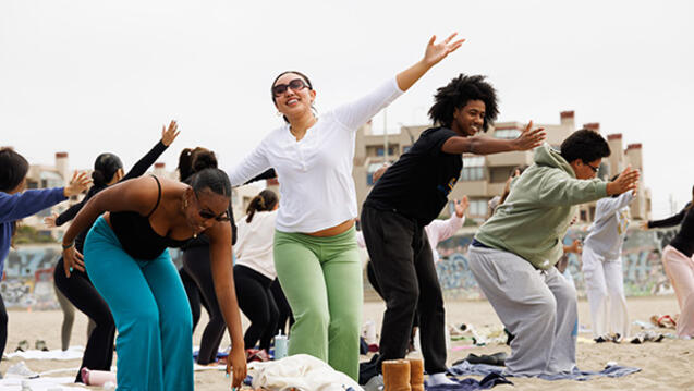 students doing yoga poses at the beach