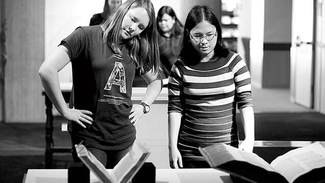 Kathryn Booth ’15 (left) and Sabrina Oliveros ’15 position a book at a student-curated exhibit at Thacher Gallery.