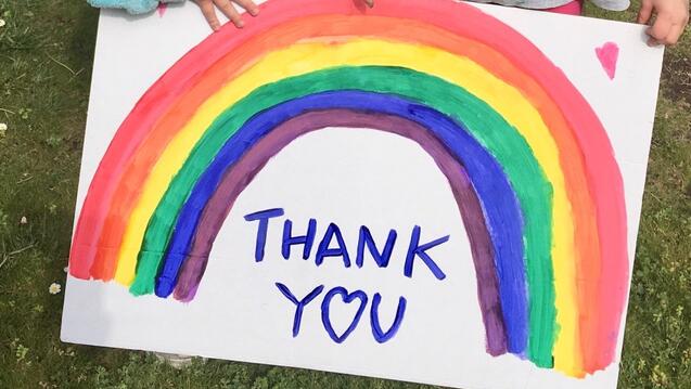 The words "thank you" on a sign with a drawing of a rainbow above the words.