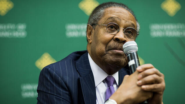 Dr. Clarence B. Jones holds a microphone at event