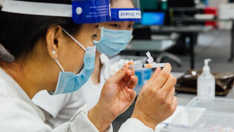 A nursing student holds a syringe with a cap on