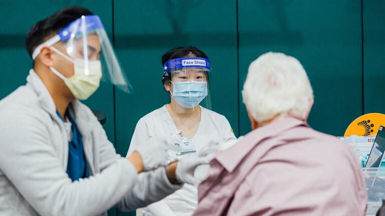 Registered nurse administers injection to patient while nursing student observes