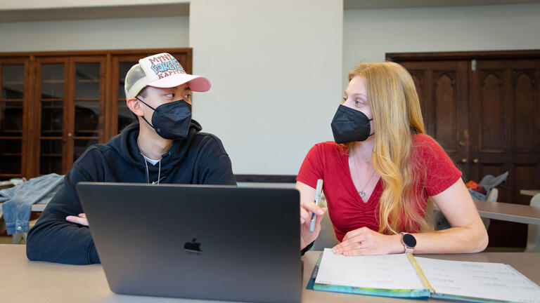 Two students work together on a laptop.