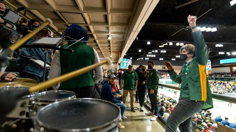 USF marching band led by band director sit in rafters and play at Sobrato Center