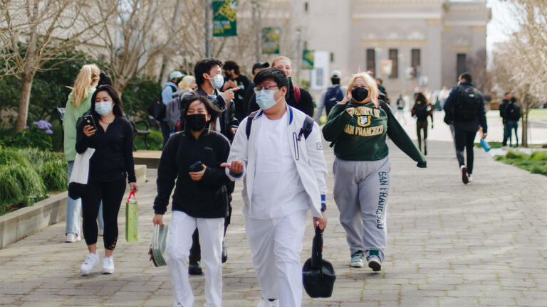Nursing students and others walk through the center of campus