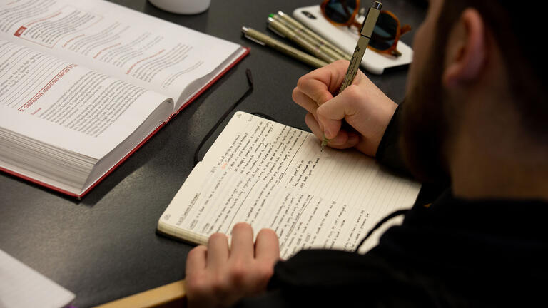 Student writes notes in a notebook in class.