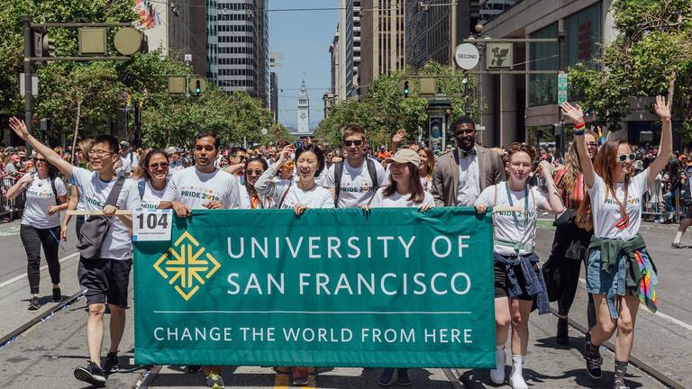 Students and staff carry a USF banner in the SF Pride Parade.