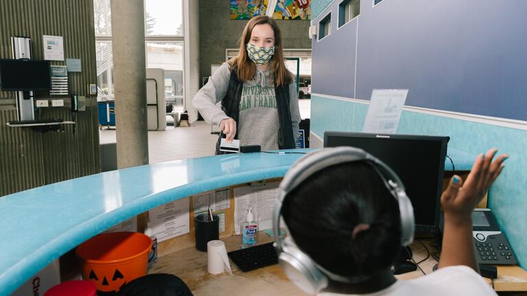 Front desk worker welcoming patron at Koret