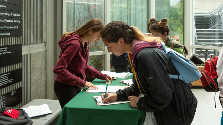 Person signing paper in Koret lobby