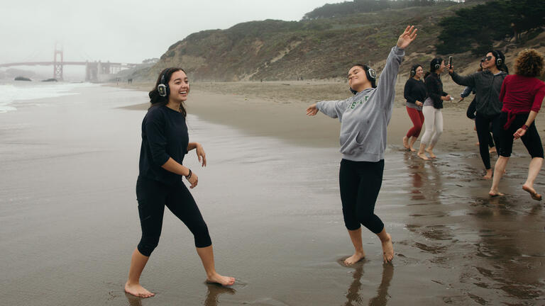 Students spin and dance on Baker Beach in SF.