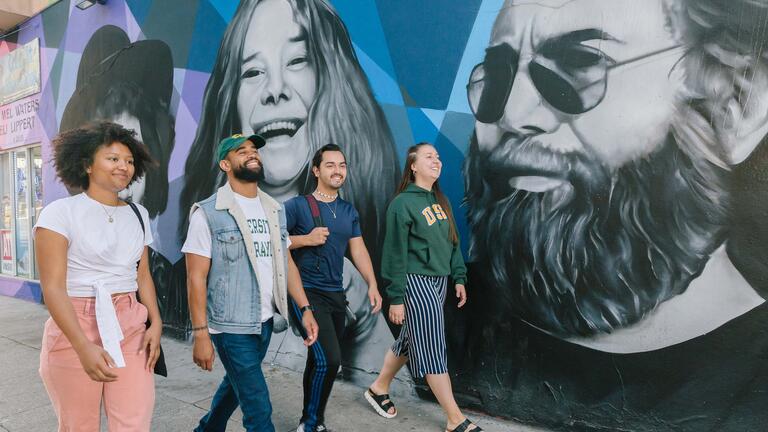 Students walk Haight Street past murals of Janice Joplin and Jerry Garcia.