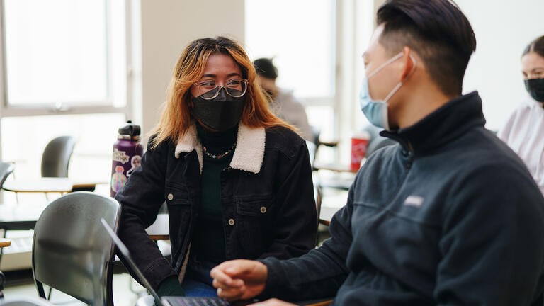 Two students discuss a point in class.