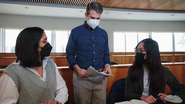 Professor speaks to two students in class.