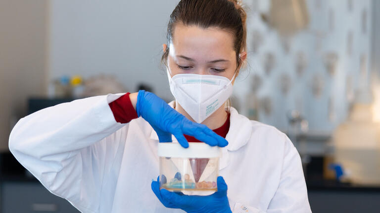 Student holds a sample in a jar in lab class.