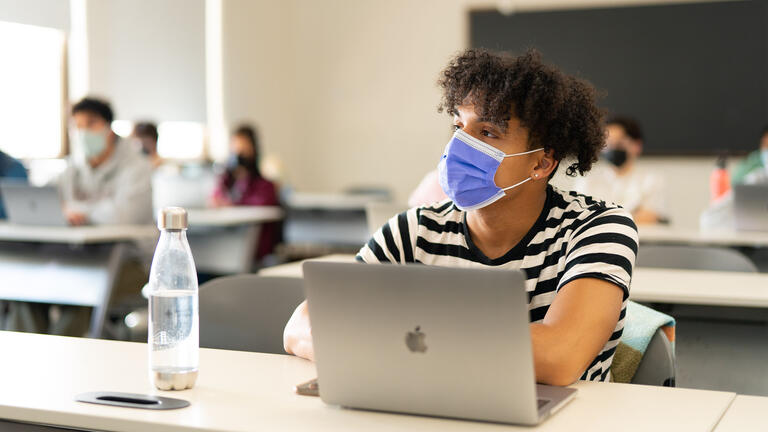 Student with a laptop pays attention in class.