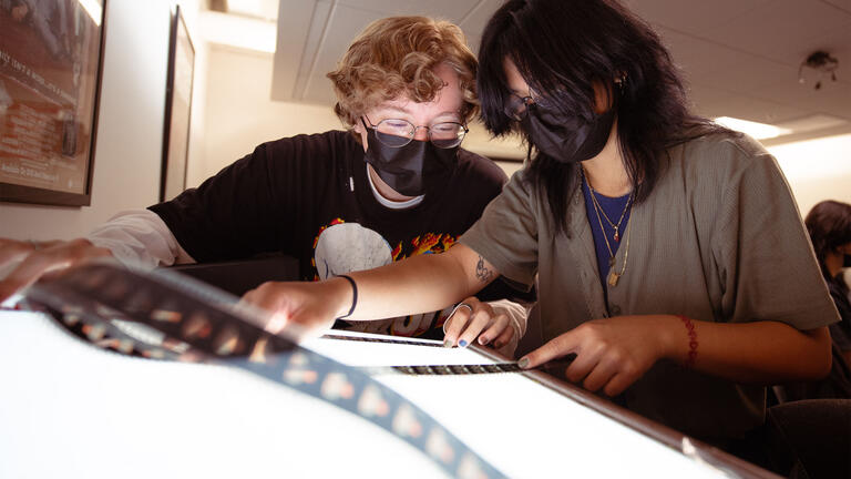 Film students inspect a strip of film at a light table.