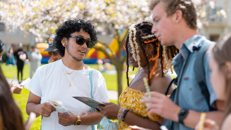 Students gather and talk at event on the lawn.