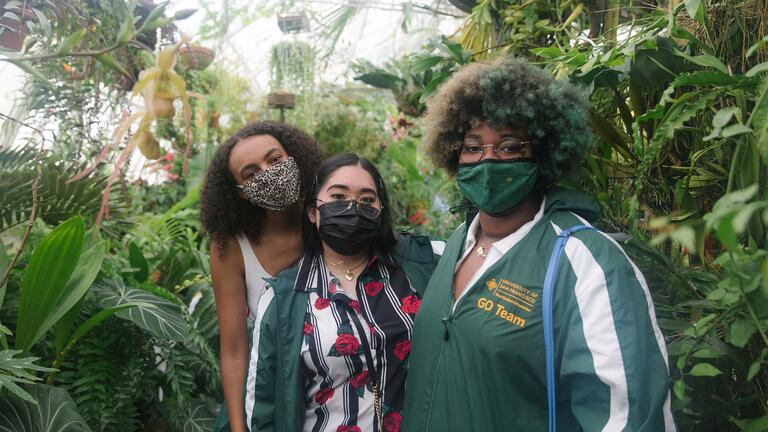 Students stand among plants in the conservatory of flowers.