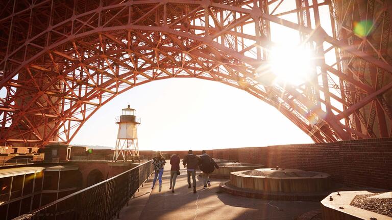 A group of students run through Ft Point under the Golden Gate Bridge.