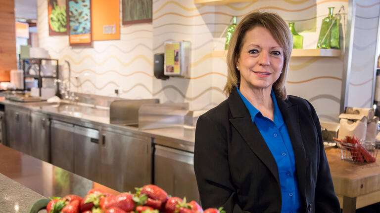 Mary Clark Bartlett stands behind a lunch counter.