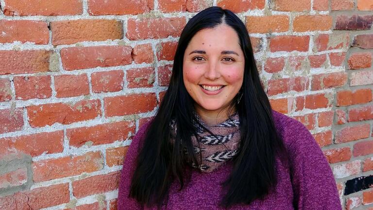 Amanda poses near a brick wall.