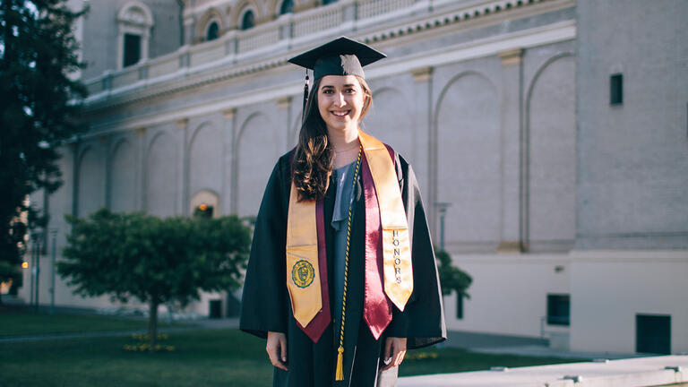 Kayla Tabari in graduation gown near St. Ignatius Church.