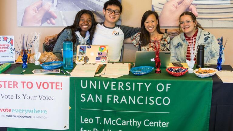 Students sitting at a booth promoting voter registration