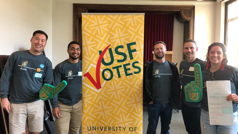 Students standing in front of a USFVotes sign