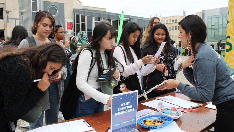 Students filling out forms at a voting booth