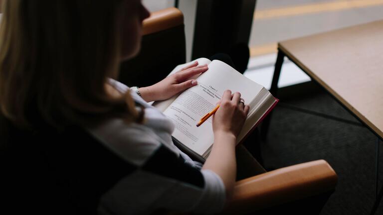 Student reads book while sitting in chair