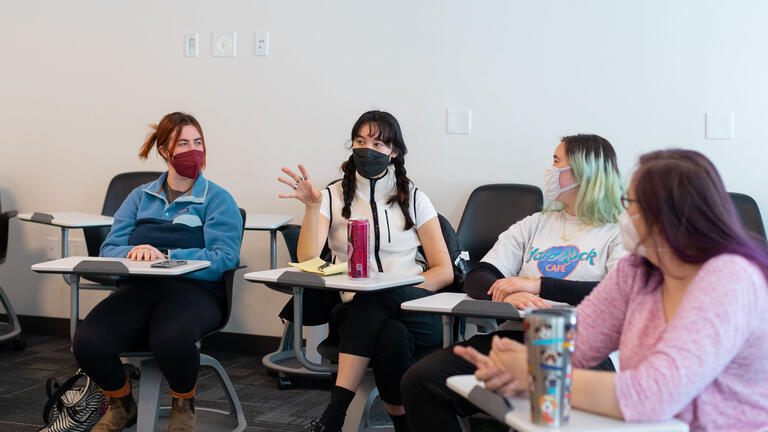 A student talks and points while the other three listen