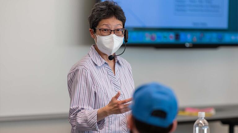 Management professor wearing a headset lecturing in class
