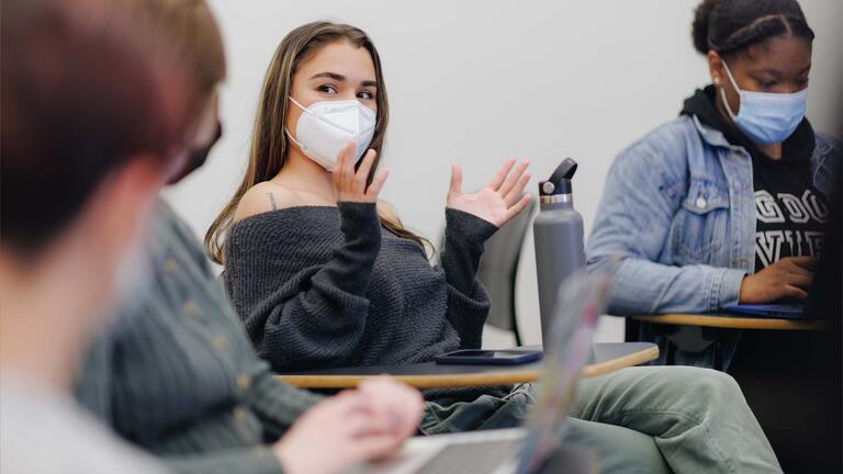 A student gestures with hands while others listen