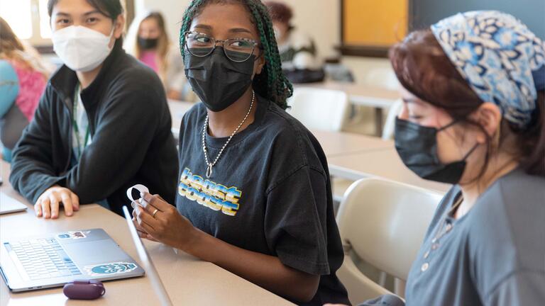 Student looks at another student sitting at the same table