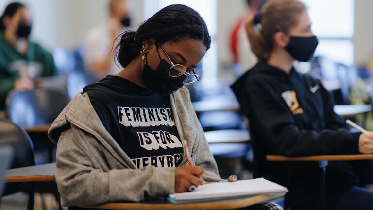 Student diligently writes in a notebook in class