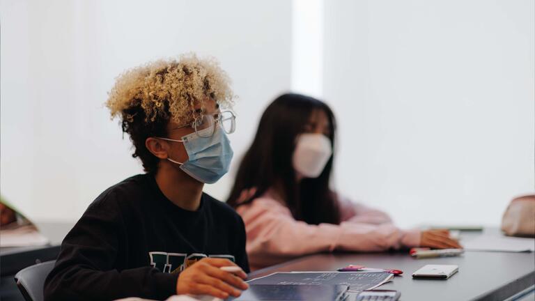 Student looks up from the tablet they are writing on in class