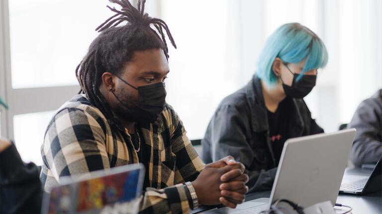 Student looks at their laptop while clasping hands