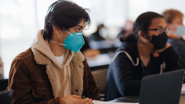 Student holding a pen gazes up from the notes they are taking