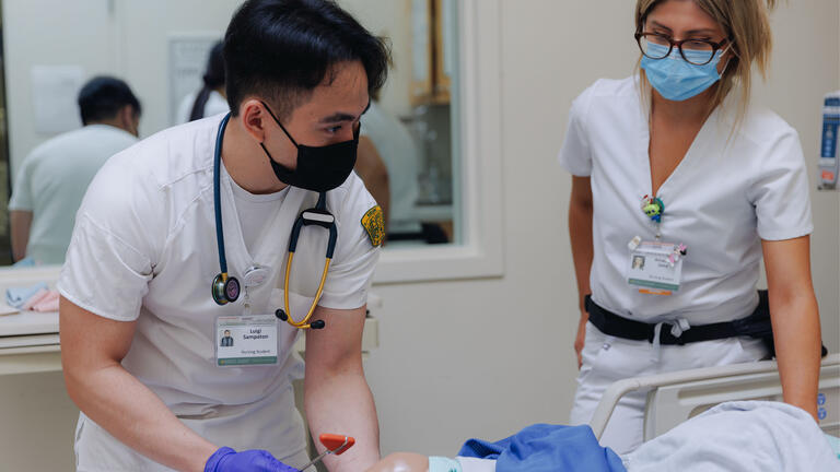 Nursing student works on a practice dummy in the sim lab.