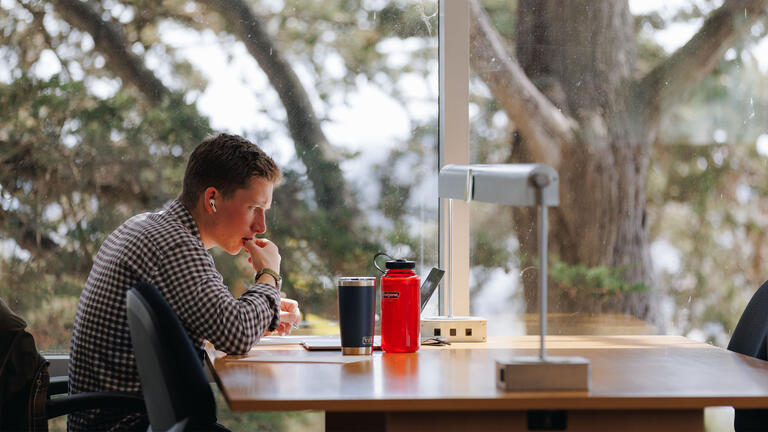 Student studies at a table in the library.