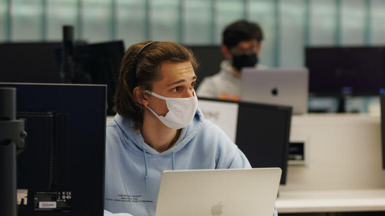 Student with a laptop looks to the side while listening in a computer lap