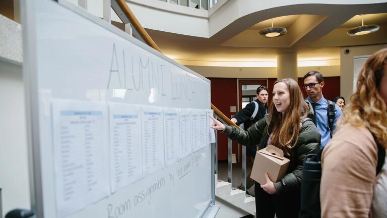 Person stands in front of white board and points