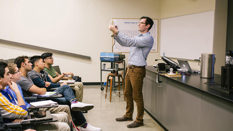 Professor demonstrating physics in front of class.