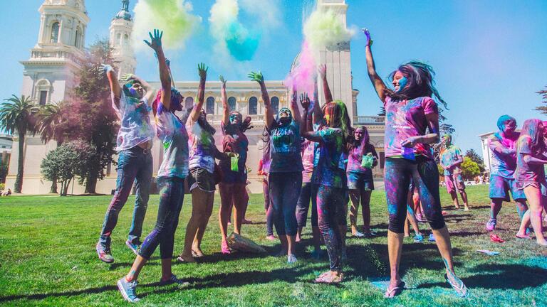 Students jumping up and throwing colorful powder during Holi festival