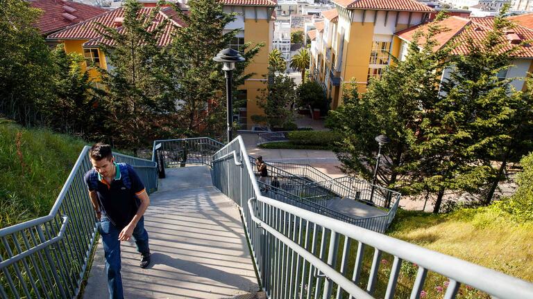 Student walking up stairs with view of Loyola Village in the background