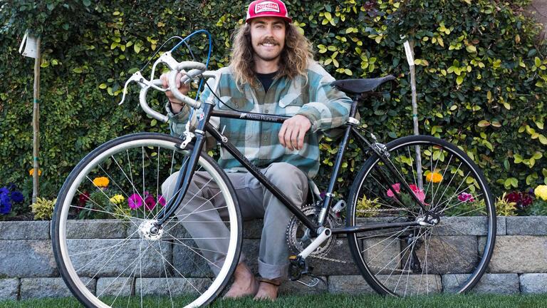 Student sits on wall behind bike