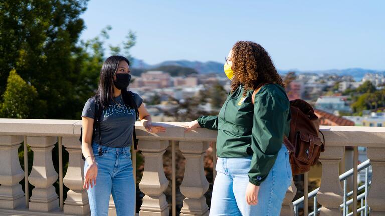 Two students overlooking the city while talking to each other