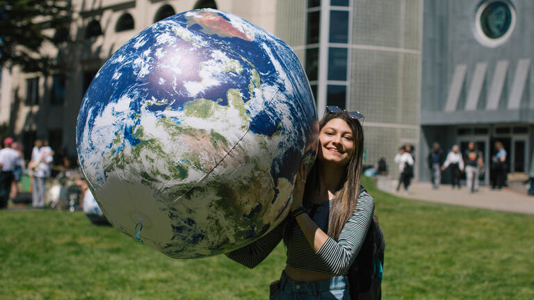 Student holding a large earth shaped ball